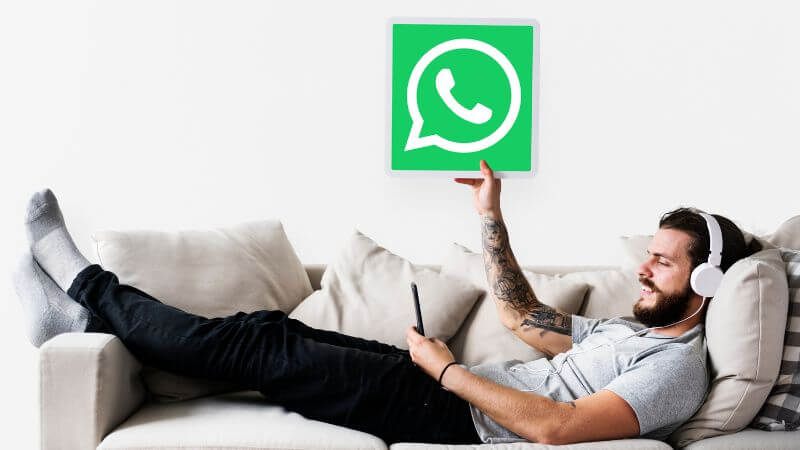 homem deitado no sofá segurando ícone do WhatsApp